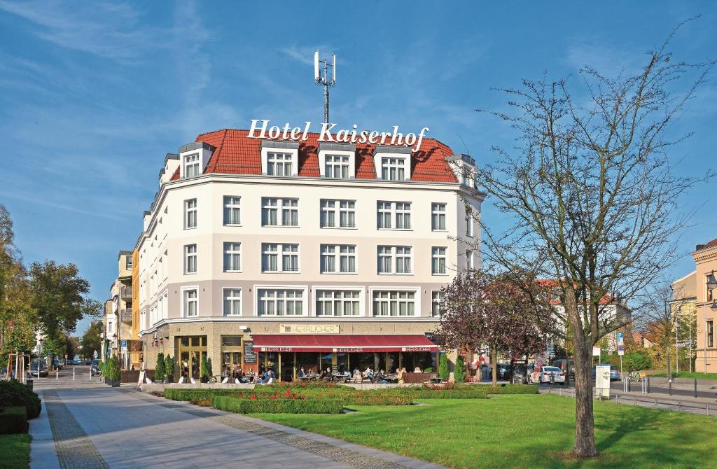 een groot wit gebouw met een rood dak bij Hotel Kaiserhof in Fürstenwalde