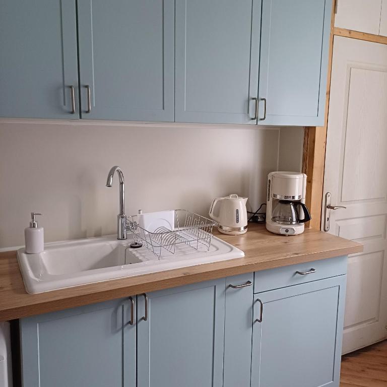 une cuisine avec des armoires blanches et un évier dans l'établissement L'Epicerie Maison années 30, à Caen