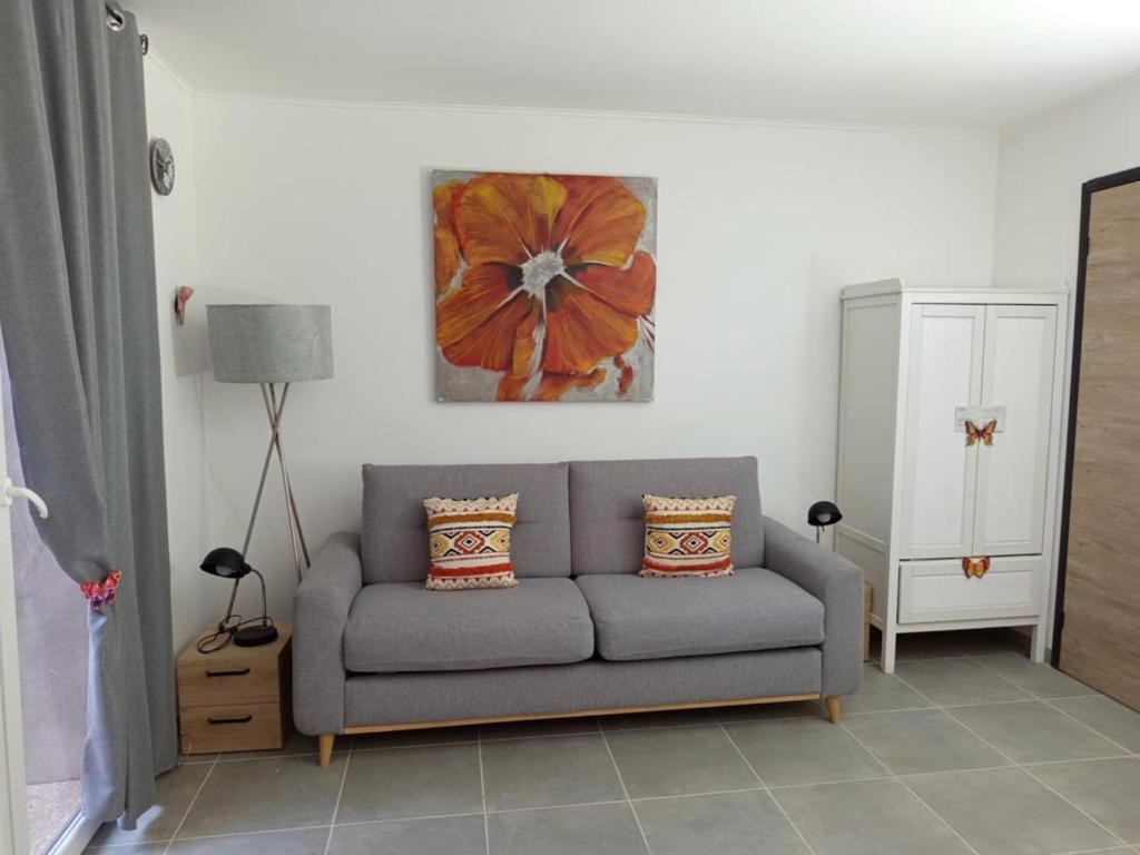 un salon avec un canapé gris et un tableau dans l'établissement Fully equipped studio, à Saint-Germain-de-Joux