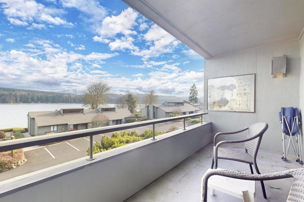 a balcony with two chairs and a view of a lake at Bayfront Retreat A in Port Ludlow
