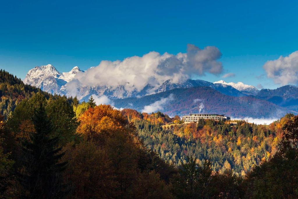a building on a hill with mountains in the background at Kempinski Hotel Berchtesgaden in Berchtesgaden