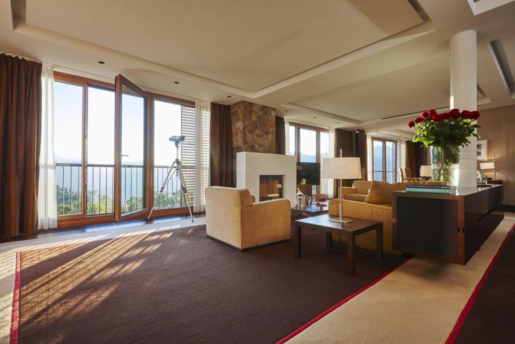 a living room with a couch and chairs and windows at Kempinski Hotel Berchtesgaden in Berchtesgaden
