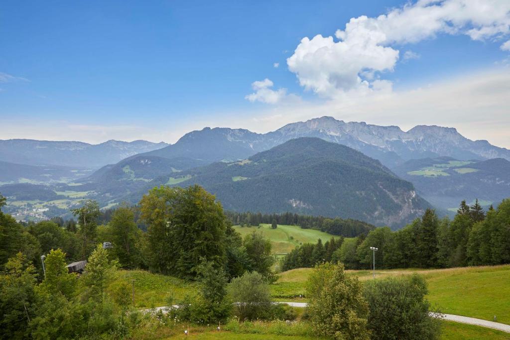 a green field with mountains in the background at Kempinski Hotel Berchtesgaden in Berchtesgaden