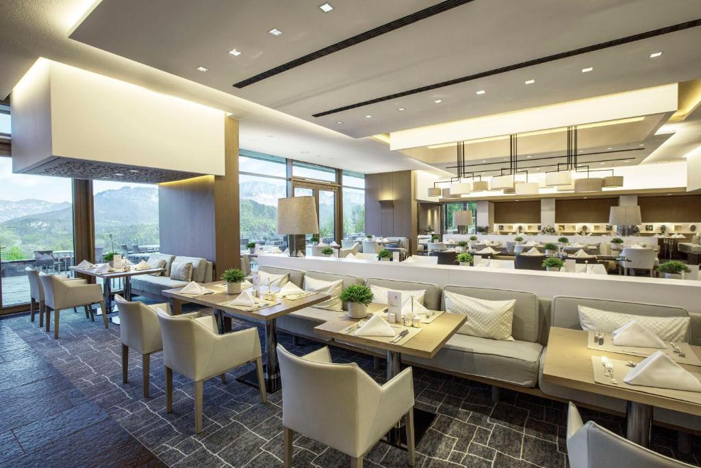 a restaurant with tables and chairs and a bar at Kempinski Hotel Berchtesgaden in Berchtesgaden