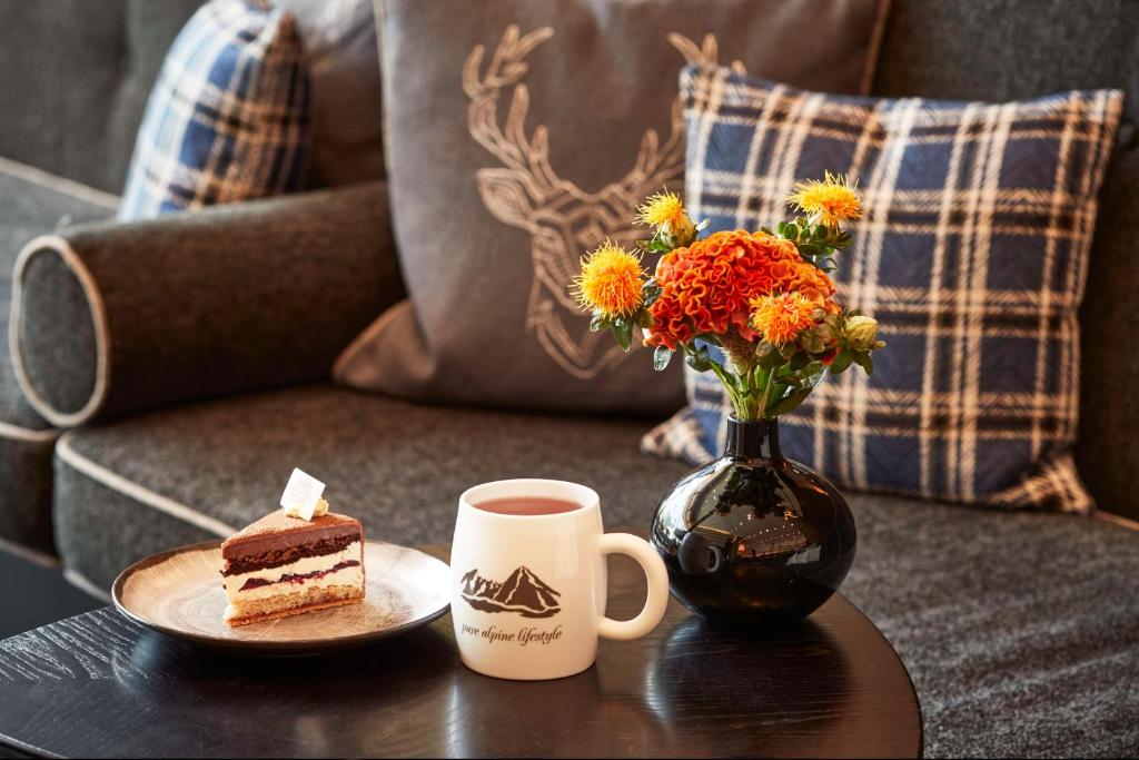 a table with a plate of cake and a vase with flowers at Kempinski Hotel Berchtesgaden in Berchtesgaden
