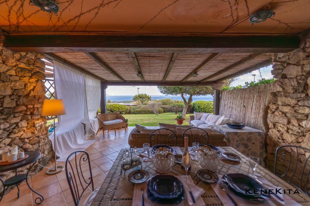 Un patio con mesa y sillas y un muro de piedra. en Dream the Sea, en Porto Rotondo