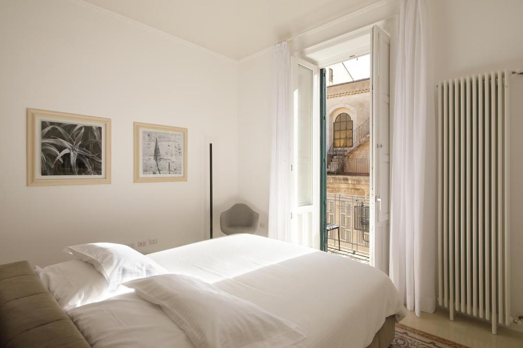 una camera da letto bianca con un letto e una finestra di L'arco di San Giuseppe a Siracusa