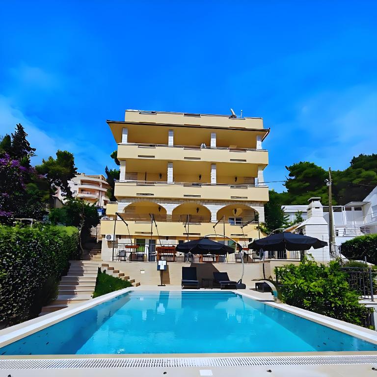 a hotel with a swimming pool in front of a building at Villa Penava, private beach, pool and 7min to Trogir in Trogir