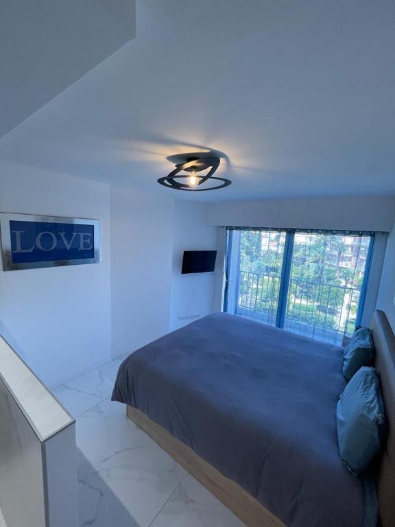 une chambre avec un lit et un ventilateur de plafond dans l'établissement Modern Chic Seaview Appartement, à Cannes