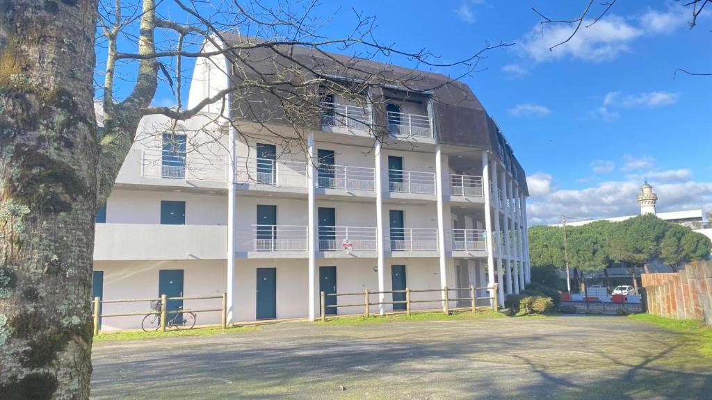 un grand bâtiment blanc avec un arbre devant dans l'établissement Le petit Studio, à Saint-Nazaire