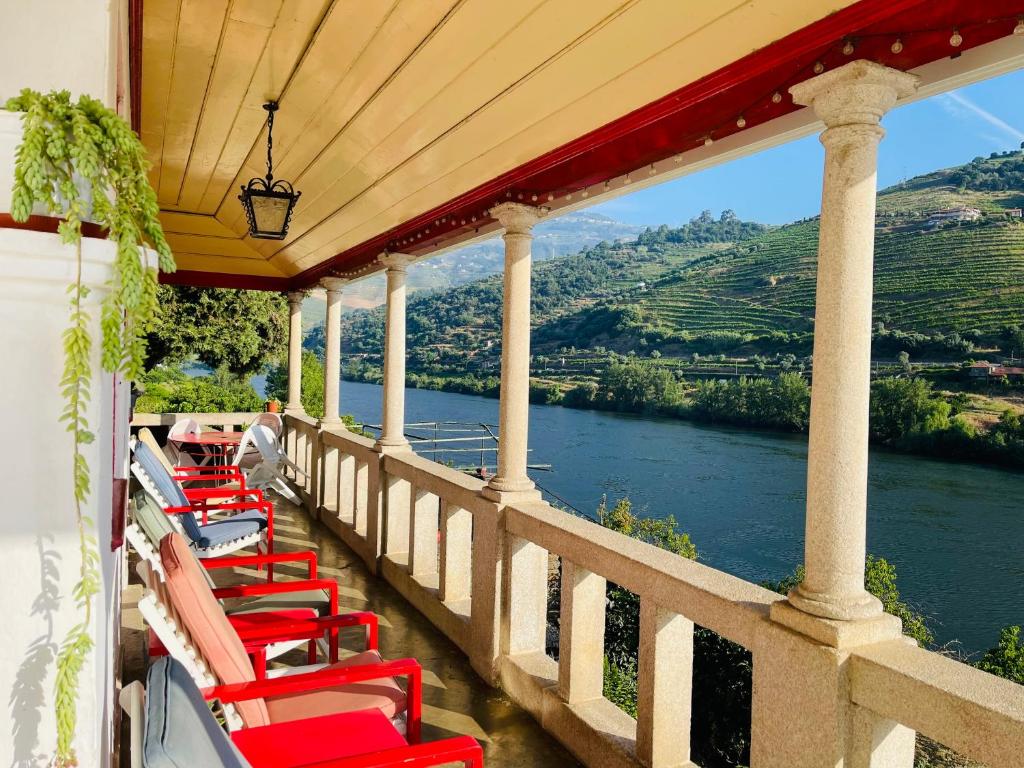 een rij rode stoelen op een balkon met uitzicht op een rivier bij Historic Douro Valley Quinta in Lamego