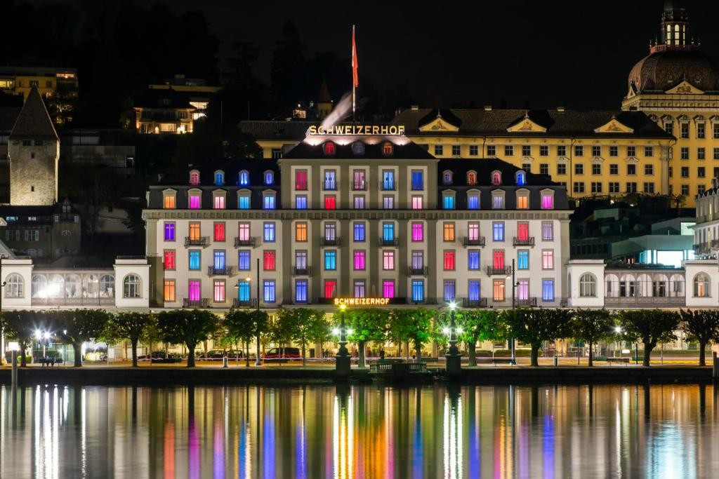 a large building with colorful lights on the water at night at Hotel Schweizerhof Luzern in Lucerne