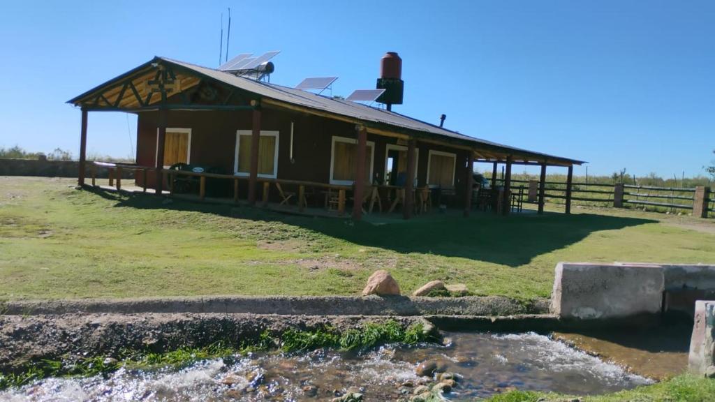ein Haus auf einem Hügel neben einem Fluss in der Unterkunft Ruedas Negras Casa de Campo in Los Árboles