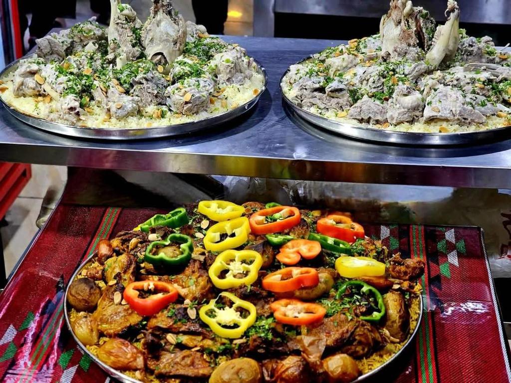 zwei Pizzen mit Tomaten auf dem Tisch in der Unterkunft Nassen House in Udhruḩ