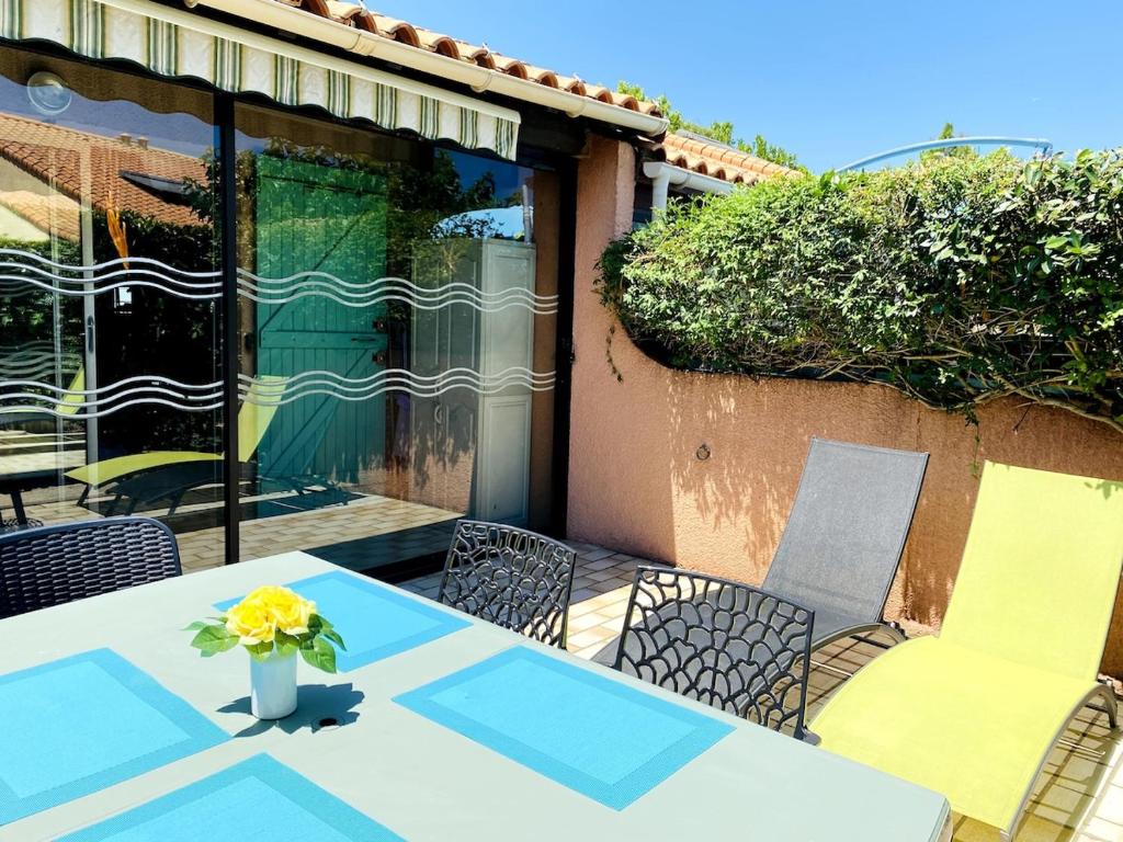 une table et des chaises avec un vase de fleurs. dans l'établissement Villa de vacances à la Marina avec WIFI proche plage, à Saint Cyprien Plage