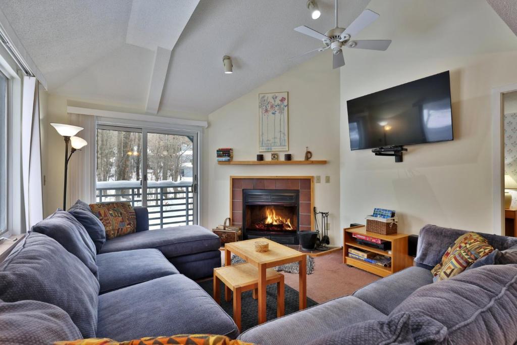 a living room with two couches and a fireplace at Woods Resort and Spa - Cozy 2-Bedroom Condo Minutes to Ski Resort - Spa, Pool, Hot Tub, Tennis, Fireplace in Killington