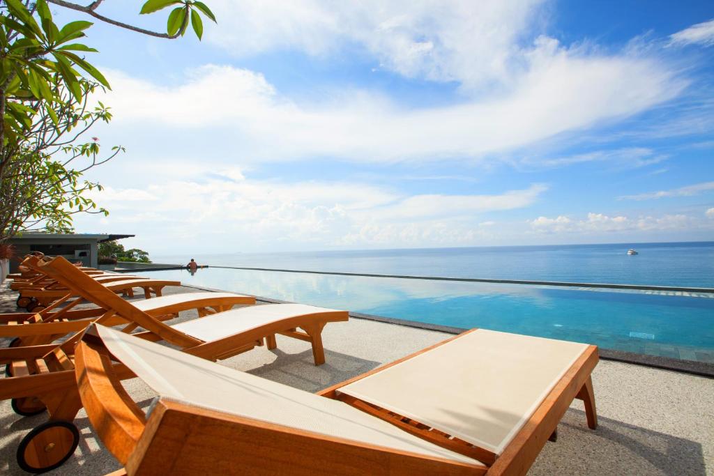 a pool with chairs and a view of the ocean at Norn Talay Surin Beach Phuket in Surin Beach