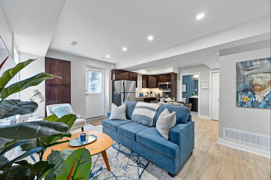 a living room with a blue couch and a kitchen at Casa St Clair - Family Suite w Patio in Toronto