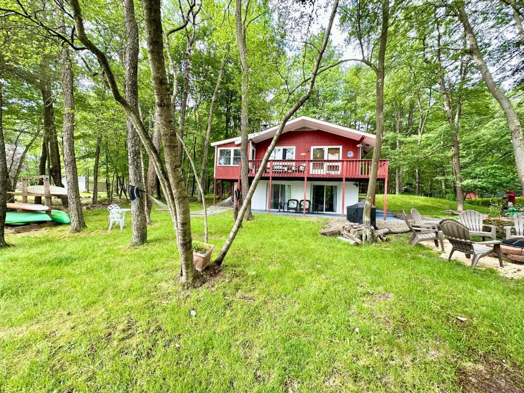 una casa roja en medio de un parque en Peaceful Pocono Lakefront, beach, pools, firepit, pets, en Arrowhead Lake