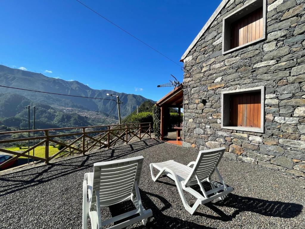 two white chairs sitting on a patio with a building at Zef's Cottage in São Vicente