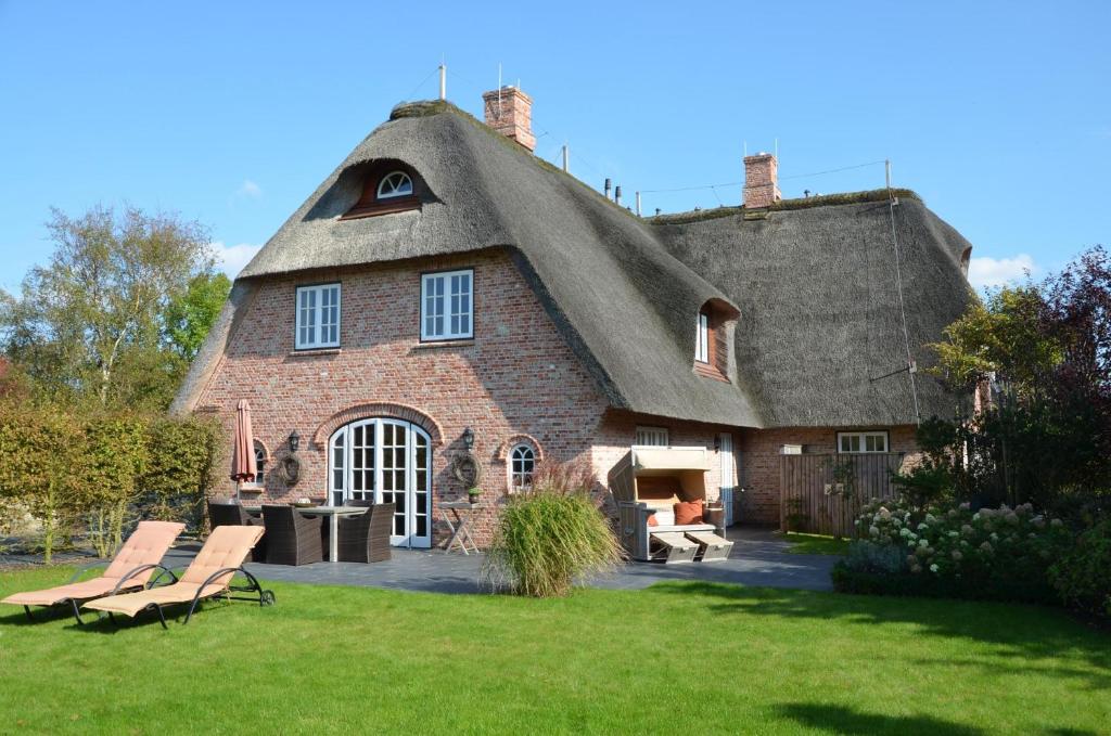 a thatch roofed house with two chairs in a yard at LITZKOW 15808 in Morsum
