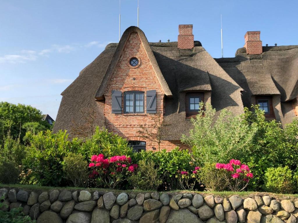 una casa con il tetto di paglia e dei fiori davanti di LITZKOW 16201 ad Archsum