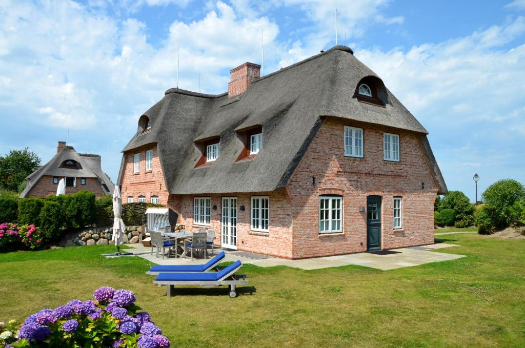 una grande casa con il tetto di paglia con un tavolo e delle sedie di LITZKOW 16203 ad Archsum