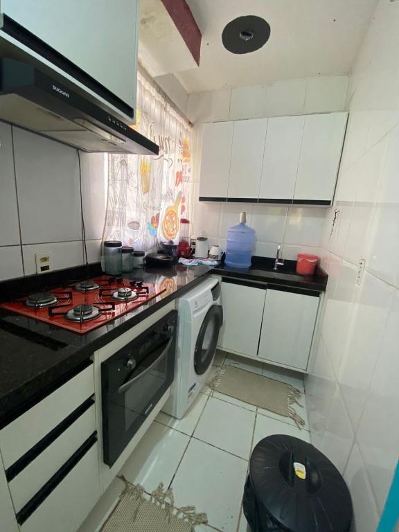 a kitchen with a stove and a washing machine at Apartamento da Letícia in Camaçari