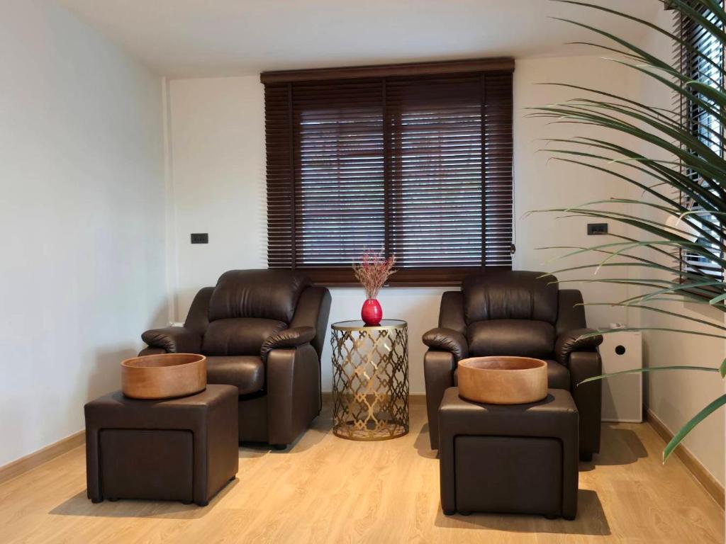 A small seating nook with two leather armchairs, footstools and a shuttered window.