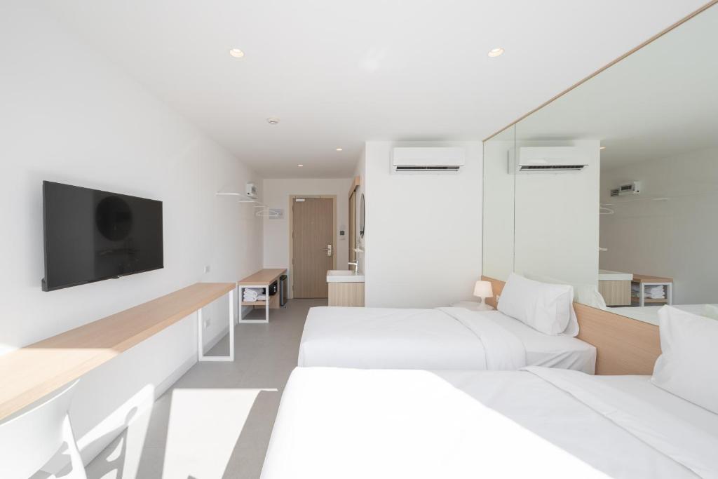 A bright twin room with mirrored storage, air conditioning and a long television console.