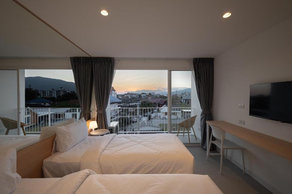 A twin room opening onto a balcony with a mountain-and-city sunset view.