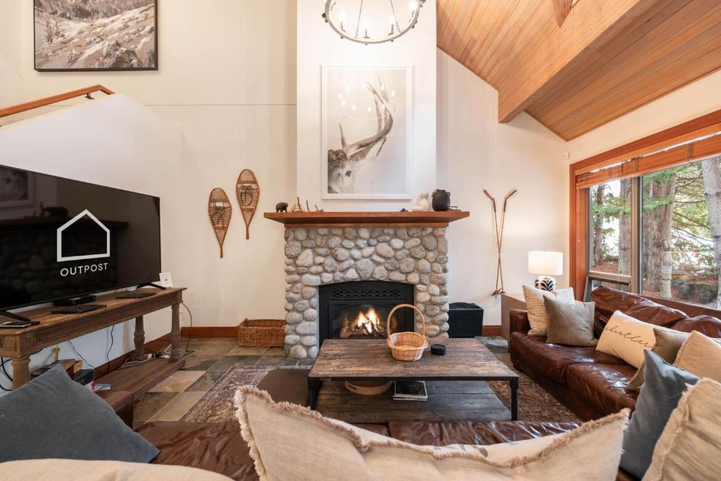 een woonkamer met een bank en een open haard bij Montebello 4877 by Outpost Whistler in Whistler