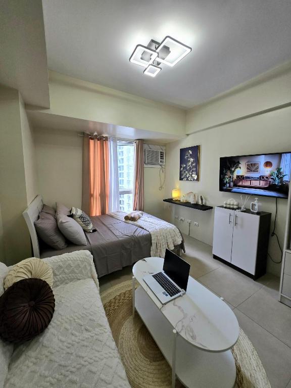 a bedroom with a bed and a laptop on a table at Pool view Studio with WiFi & Netflix , Avida Riala in Cebu City