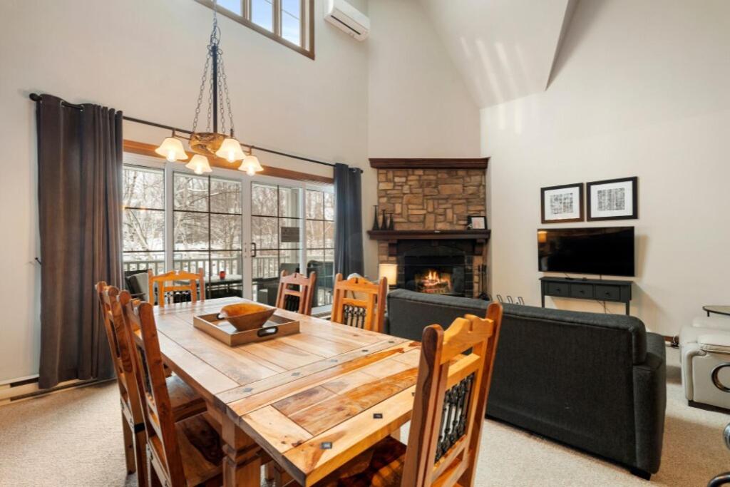 a dining room with a wooden table and a fireplace at Les Manoirs 3bdrs Near Village in Mont-Tremblant
