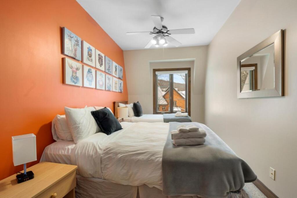 a bedroom with a large bed with orange walls at Les Manoirs 3bdrs Near Village in Mont-Tremblant