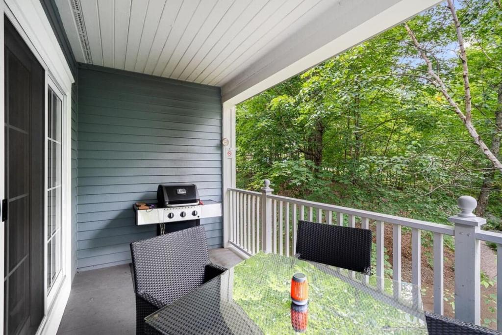 a patio with a table and chairs on a porch at Les Manoirs 3bdrs Near Village in Mont-Tremblant