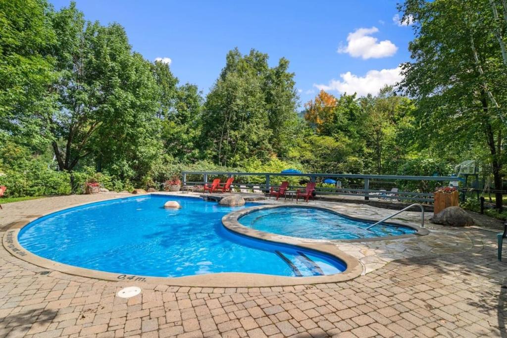 a swimming pool in a yard with a brick patio at Les Manoirs 3bdrs Near Village in Mont-Tremblant