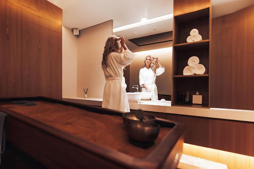 a woman standing in front of a mirror in a bathroom at FIVE Jumeirah Village in Dubai