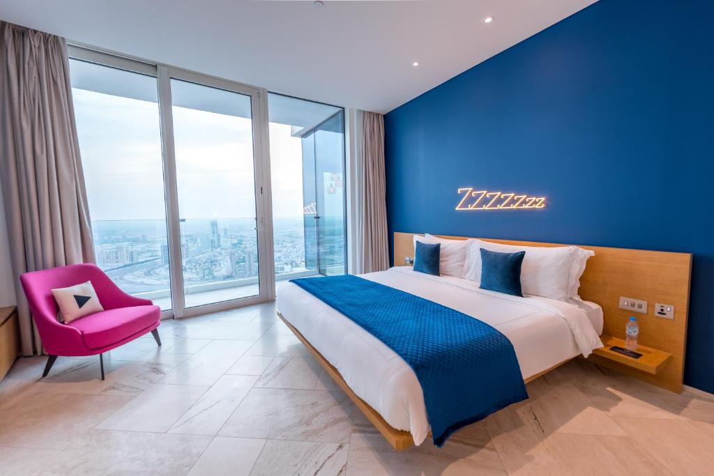 a bedroom with a large bed and a pink chair at FIVE Jumeirah Village in Dubai