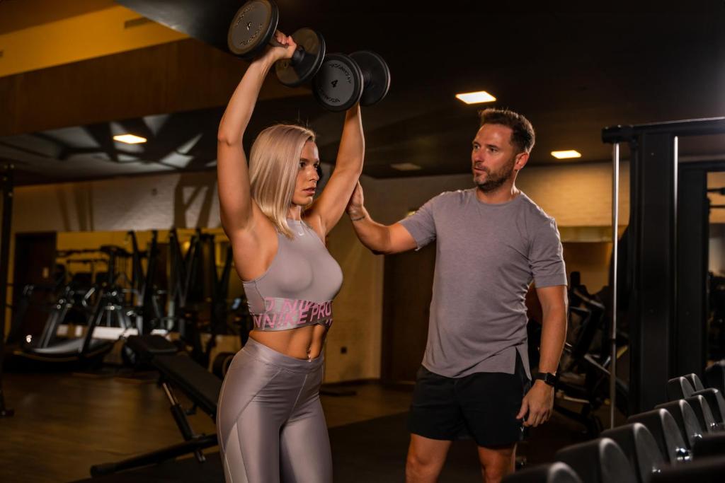 a man and a woman lifting weights in a gym at FIVE Jumeirah Village in Dubai