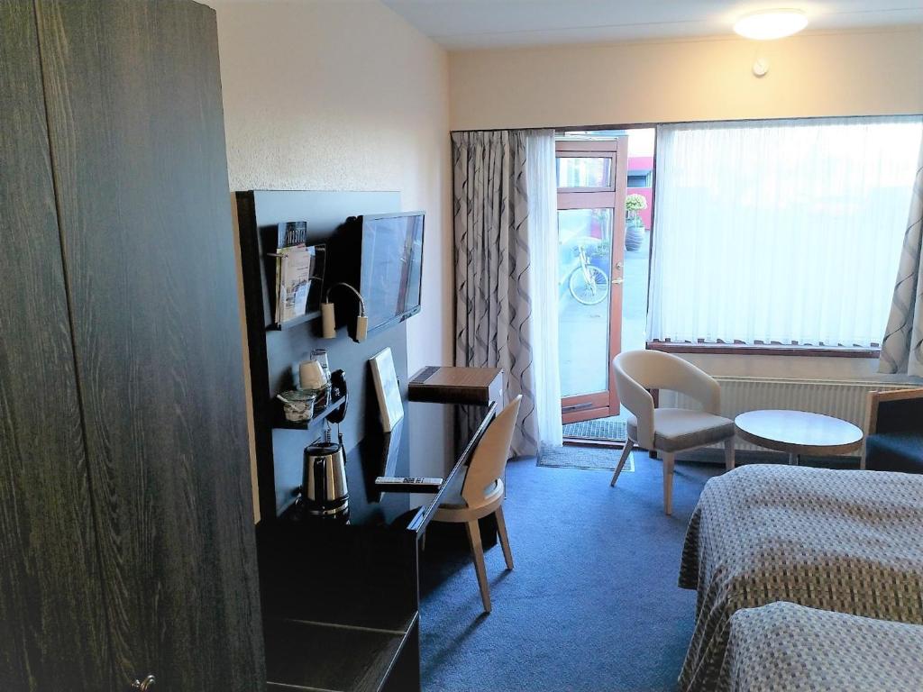 a hotel room with a bed and a table and a room at Hotel Falster in Nykøbing Falster