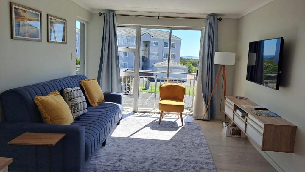 a living room with a blue couch and a sliding glass door at Breezy Sunny Apartment in Cape Town