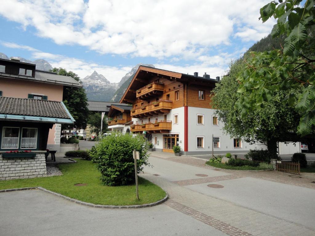 a building in the middle of a town with mountains at Appartements Schmidsendl in Lofer