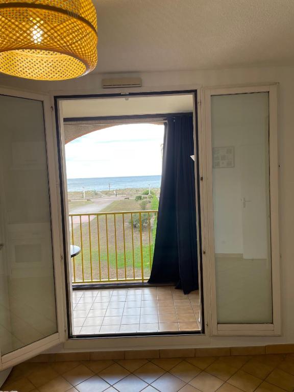 d'une porte coulissante en verre offrant une vue sur la plage. dans l'établissement Le Palm Beach vue mer le Barcares, au Barcarès