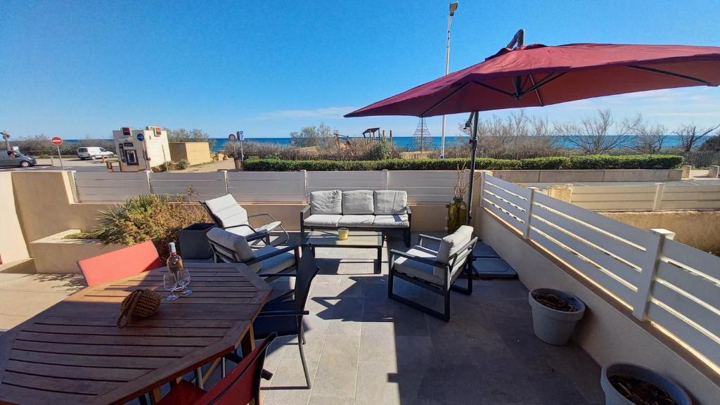 un patio avec des tables et un parasol sur le toit dans l'établissement Appartement 2 pièces climatisé 3 couchages, Belle Terrasse VUE MER à Portiragnes plage LXBFM9, à Portiragnes