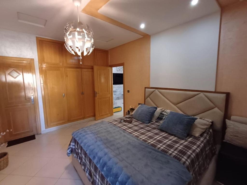 Un dormitorio con una cama y una lámpara de araña. en Belle vacances dans mon App, en Meknès