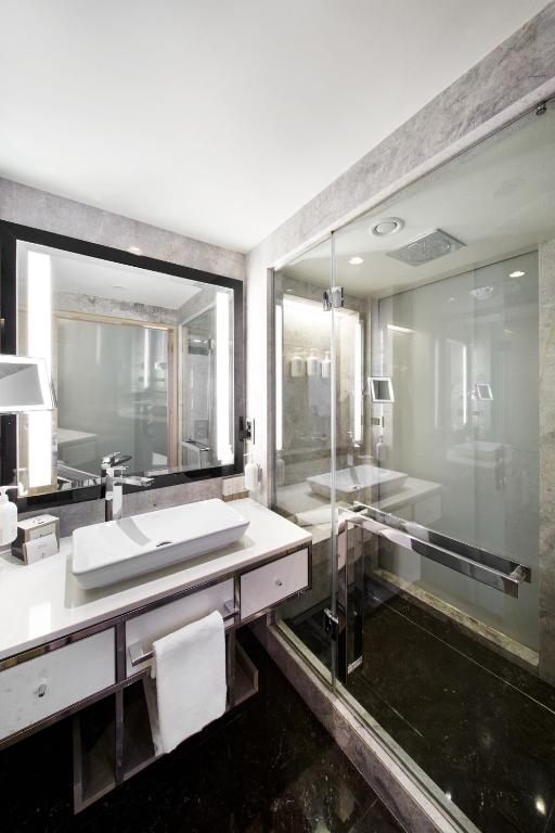 a bathroom with a sink and a large mirror at The Marmara Taksim in Istanbul