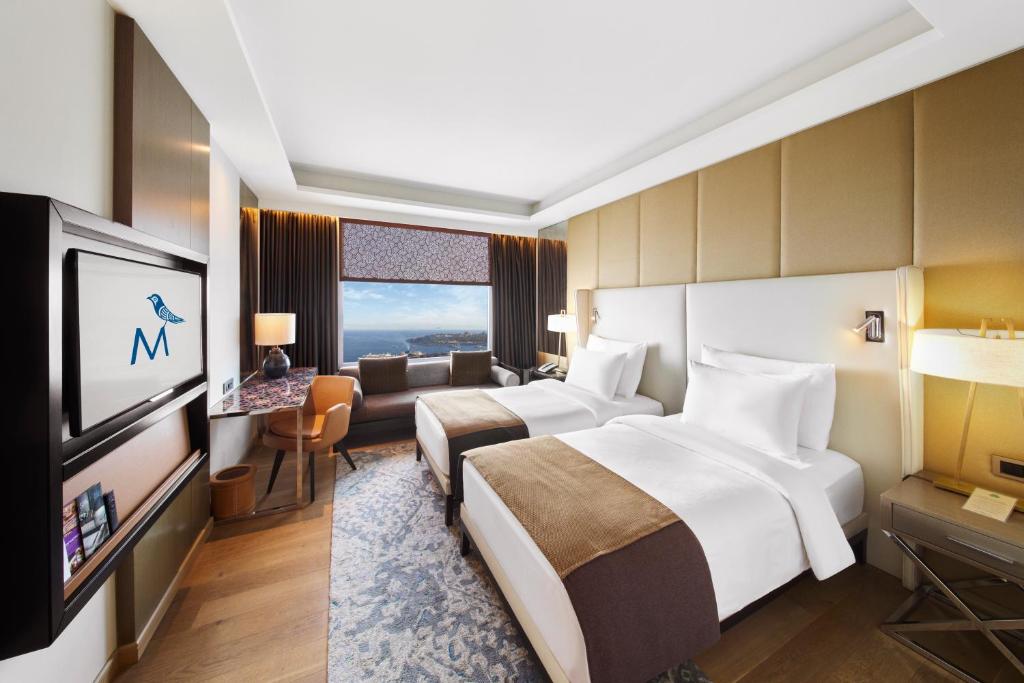 a hotel room with two beds and a flat screen tv at The Marmara Taksim in Istanbul