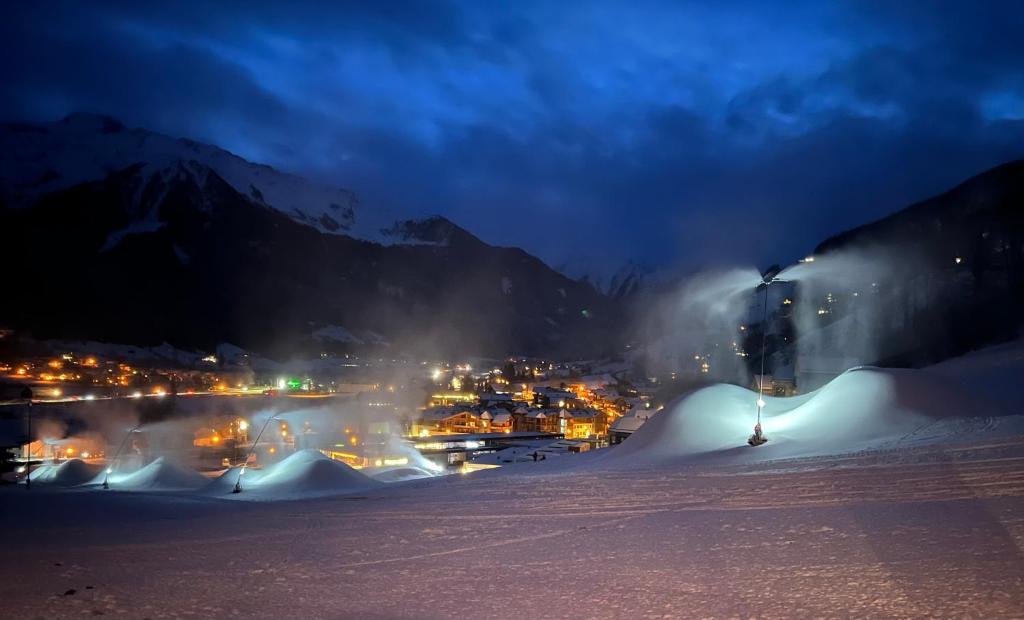 einen schneebedeckten Hang in der Nacht mit einer Stadt in der Unterkunft Wildkogel-Villa in Bramberg am Wildkogel