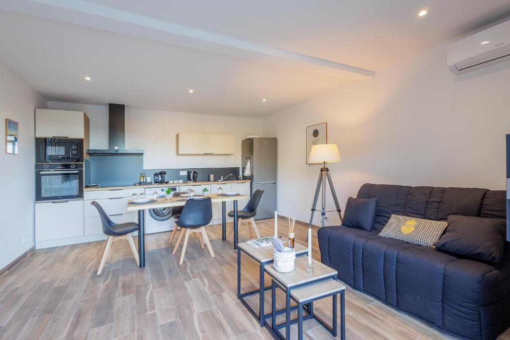 a living room with a blue couch and a kitchen at La Casa Di Castagni - Climatisé avec terrasse in Oletta